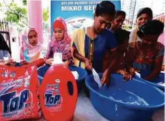  ??  ?? PENGHUNI rumah kebajikan diajar mencuci pakaian dengan serbuk pencuci Top.