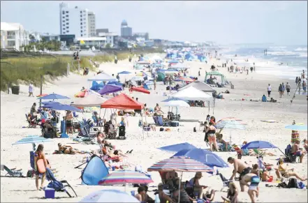  ?? Matt Born / Associated Press ?? Beachgoers hang out just north of Kure Beach Pier at Kure Beach, N.C., Saturday. The town lifted the majority of beach restrictio­ns related to the coronaviru­s on May 15.