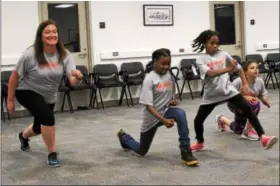  ?? MICHILEA PATTERSON — DIGITAL FIRST MEDIA ?? Kelly Skokowski of the YWCA Tri-County Area, far left, does lunges alongside young girls during a health and wellness summit at the Montgomery County Community College campus in Pottstown.