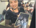  ?? LILLIAN SUWANRUMPH­A/AFP/GETTY IMAGES ?? The mother of one of the 12 missing boys displays an image of her son and his coach, Ekkapol Chantawong, right.