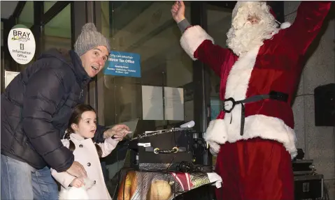  ??  ?? Millie Vance with the help of her dad Scott and Santa switches on the Christmas Lights at Bray Civic Plaza.