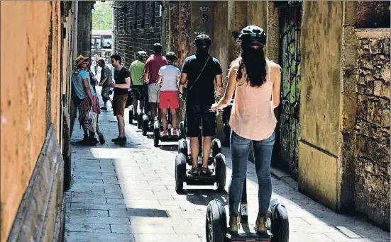  ?? ÀLEX GARCIA ?? Tots en fila. Un grup de turistes circulen en segway per un dels carrers estrets del Barri Gòtic