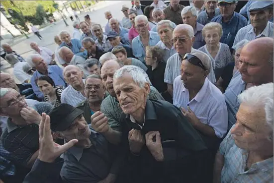  ?? EMILIO MORENATTI / AP ?? Protestas de pensionist­as ante una oficina bancaria contra el límite de 120 euros de retirada de efectivo a la semana