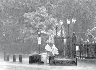  ?? Associated Press ?? People walk on a street during a downpour Sunday in the French Quarter in New Orleans. Tropical Depression Barry dumped rain as it slowly swept inland through Gulf Coast states Sunday, sparing New Orleans from a direct hit but stoking fears elsewhere of flooding, tornadoes, and prolonged power outages.