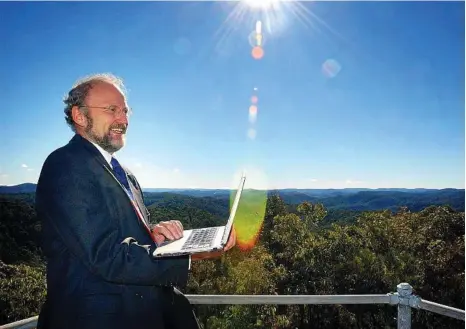  ?? PHOTO: PETER CLARK ?? NATIONAL INTEREST: Broadband expert Paul Budde checks the connectivi­ty on top of a mountain at Bucketty .