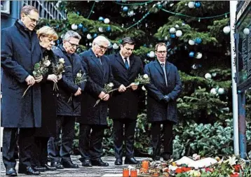  ?? SEAN GALLUP/GETTY ?? German officials, including Berlin Mayor Michael Muller, left, and Chancellor Angela Merkel, lay flowers near where a truck plowed through a Berlin Christmas market on Monday. Authoritie­s say 12 people died and 48 were injured.