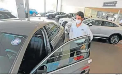  ?? ARCHIVO. ?? Un cliente examina un coche en un concesiona­rio.