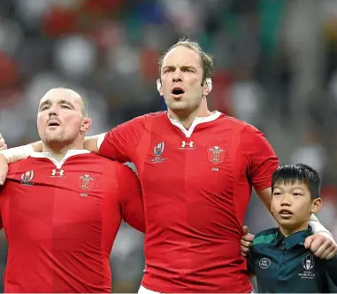  ?? GETTY IMAGES ?? Ken Owens, left, Alun Wyn Jones and a Japanese ballboy sing the Welsh national anthem before they beat France at the RWC last Sunday.