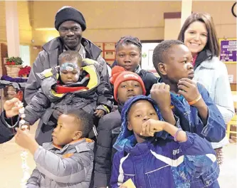  ??  ?? Melinda Forward, right, a French teacher at Del Norte High School, with Olivier Kamndon, back left, and his children. The kids are enjoying popcorn at a holiday party at New Beginnings Church of God near Carlisle and Montgomery.