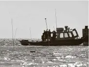  ?? Ian Terry / Contributo­r file photo ?? Workers plant poles to mark out areas for proposed reef rows off the coast of Matagorda in 2013.