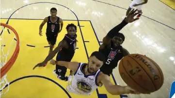  ??  ?? Stephen Curry (front) of the Golden State Warriors goes up for a shot on Montrezl Harrell (right) of the LA Clippers during Game One of the first round of the 2019 NBA Western Conference Playoffs at ORACLE Arena in Oakland, California. — AFP photo