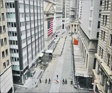  ?? John Minchillo Associated Press ?? “IT HAS BECOME clear that our economy will face severe disruption­s,” the Federal Reserve said Monday. Above is a practicall­y deserted scene around the typically bustling New York Stock Exchange area Saturday.