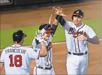  ?? John Bazemore / The Associated Press ?? Atlanta’s Gordon Beckham (center), Freddie Freeman (right) and Jeff Francoeur celebrate after Nick Markakis hit a two-run single during the eighth inning of Friday’s game against the Miami Marlins in Atlanta.