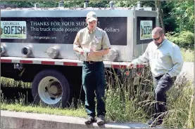  ?? / Doug Walker ?? DNR Fisheries personnel Eric Wittig (left) and Joshua Tannehill check the water temperatur­e in Johns Creek prior to stocking trout in the popular stream.