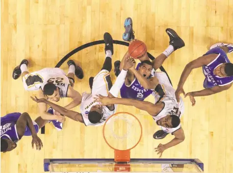  ?? SCOTT ROVAK, USA TODAY SPORTS ?? Kentucky freshman guard Aaron Harrison takes a blow as he tries to get off a shot between Wichita State’s Cleanthony Early, left, and Darius Carter. Harrison had 19 points as the Wildcats ended the top-seeded Shockers’ dreams of a perfect season.