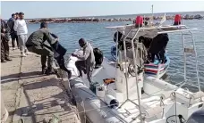  ?? Reuters ?? A member of Tunisia’s coastguard helps a migrant child to climb off a rescue boat in the city of Sfax on Saturday