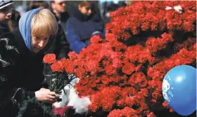  ?? Vasily Maximov / AFP / Getty Images ?? A woman lays flowers in tribute to the 62 people who died when a FlyDubai jetliner nose- dived and crashed Saturday in the Russian city of Rostov- on- Don.