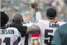  ?? MITCHELL LEFF/GETTY IMAGES ?? Philadelph­ia Eagles defensive end Chris Long, right, puts his arm around Malcolm Jenkins as Jenkins holds his fist in the air during the U.S. national anthem on Thursday in Philadelph­ia.