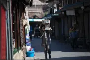  ??  ?? A laborer carries goods Friday at a market in Srinagar in Indian-controlled Kashmir.
(AP/Mukhtar Khan)