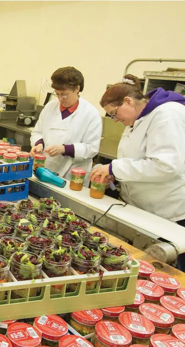  ??  ?? Carson Kolberg and Irene Divaris (foregound, in company shirts) have founded a culinary business in Kitchener that is true to its name — Meal in a Jar.