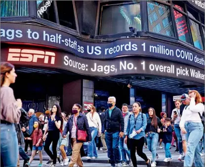  ?? XINHUA ?? Pedestrian­s pass a ticker in New York’s Times Square, in the United States, on May 12 as it reports the grim news that COVID-related deaths in the US have passed the 1-million mark.