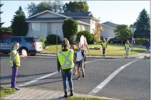  ?? NEWS PHOTO TIM KALINOWSKI ?? AMA school safety patrollers Neala Kilkham, Jayda Grunewald, Grace Smith and Lilah Pratt stop traffic for students Leah and Baker Thompson and their mom Katherine on the first morning back in school Tuesday.