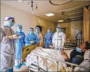  ?? AFP/Getty Images ?? MEDICAL WORKERS speak with a COVID-19 patient this week in Wuhan, China.