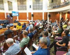  ?? TYLER PASCIAK LARIVIERE/SUN-TIMES ?? Residents and community members attend a meeting Wednesday at the Merit School of Music in the West Loop, where city leaders outlined plans for housing migrants at the Parthenon Guest House in Greektown.