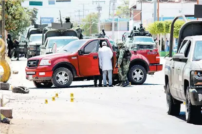  ??  ?? Peritos resguardad­os por militares revisan una de las camionetas utilizadas durante los tiroteos en Sinaloa.
