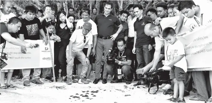  ??  ?? NEW JOURNEY. Davao Light and Power Co., Inc. President Jaime Jose “Jim” Aboitiz (center) together with the Davao Light executives, officials from Brgy. Matina Aplaya and other guests witness how the baby pawikans take on a new journey to the sea last...