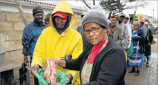  ?? Picture: EUGENE COETZEE ?? FIRST IN LINE: Shephard Meko, 54, of Soweto-on-Sea, receives some meat from Eunice Zingela in her Mabopha Street yard in Zwide