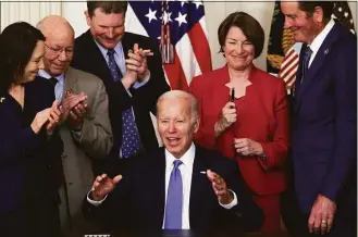  ?? Alex Wong / Getty Images ?? President Joe Biden gestures after he handed Sen. Amy Klobuchar, D-Minn., second from right, his signing pen as Sen. Maria Cantwell, D-Wash., left; Rep. Pete DeFazio, D-Ore., second from left; and Rep. John Garamendi, D-Calif., look on at the State Dining Room of the White House on Thursday. Biden signed the Ocean Shipping Reform Act of 2022 into law.
