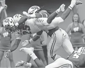  ?? MARK HOFFMAN / MILWAUKEE JOURNAL SENTINEL ?? New Mexico running back Tyrone Owens goes airborne before being tackled by D’Cota Dixon on Saturday.