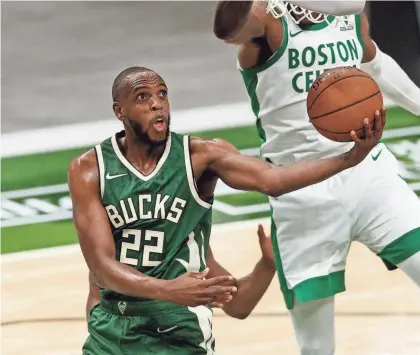  ?? JEFF HANISCH / USA TODAY SPORTS ?? Bucks forward Khris Middleton uses the rim to shield a Celtics defender Wednesday night at Fiserv Forum. Middleton finished with 27 points and 13 rebounds.