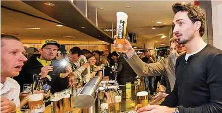  ??  ?? Pint half-full: Mats Hummels and his Dortmund team-mates typify the beer culture in Germany by serving fans