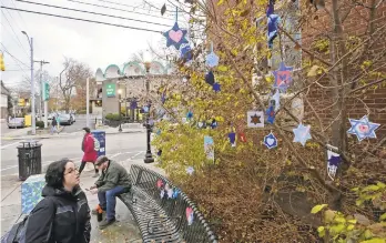  ?? GENE J. PUSKAR/AP FILE PHOTO ?? Stars of David hang from bushes in the Pittsburgh neighborho­od where 11 people were killed when a gunman opened fire Oct. 27 in a synagogue. Thousands sent donations to support the community.