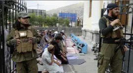  ?? Siddiqulla­h Khan/Associated Press ?? Afghan people offer Eid al-Fitr prayers as Taliban fighters stand guard at a mosque in Kabul, Afghanista­n, last year.