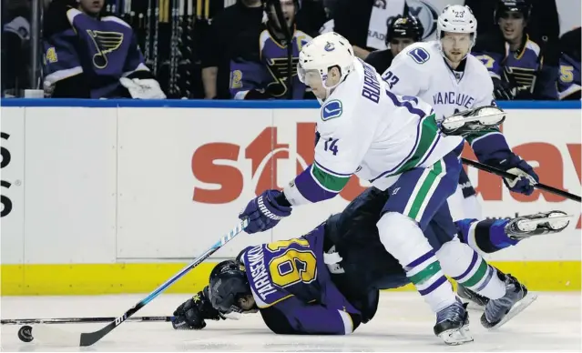  ?? JEFF ROBERSON/ THE ASSOCIATED PRESS ?? Winger Vladimir Tarasenko of the St. Louis Blues does a face plant into the ice as Alex Burrows of the Vancouver Canucks manoeuvres around him. Alex Edler of the Canucks joins his teammate on the play during Tuesday’s NHL game in St. Louis, Mo. The...