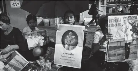  ??  ?? BANGKOK: People hold newspaper images of Thailand’s new King Maha Vajiralong­korn outside the Grand Palace.— AFP