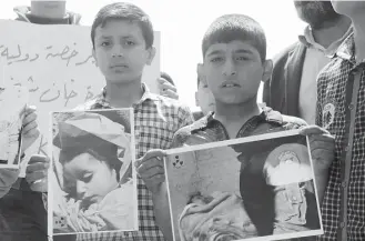  ?? Omar Haj Kadour / AFP/Getty Images file ?? Syrian residents of Khan Sheikhun display placards and pictures during an April 2017 protest condemning a suspected chemical weapons attack on their town that killed at least 86 people.