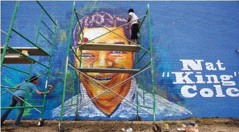  ??  ?? Artists Sunny Paulk, left, and Corey Spearman put the finishing touches on a mural of Nat King Cole last week on the side of a building in downtown Montgomery, Ala. The Nat King Cole mural, on Maxwell Boulevard overlookin­g downtown, is the second...