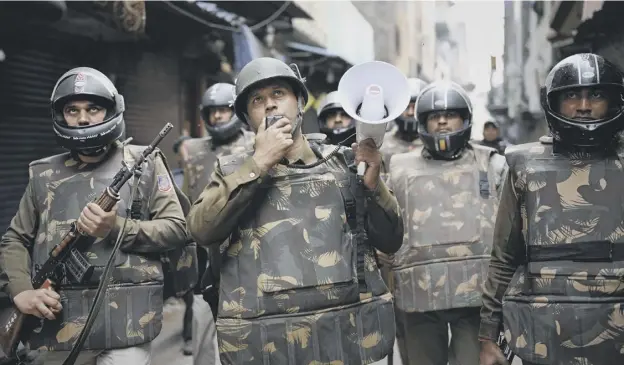  ?? PICTURE: ALTAF QADRI/AP ?? 0 Delhi police officers make announceme­nts to warn residents from venturing outside their homes