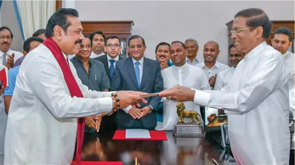  ??  ?? Sri Lanka’s former President Mahinda Rajapaksa (Front-left) is sworn in as the new Prime Minister before President Maithripal­a Sirisena in Colombo, Sri Lanka, on October 26, 2018.