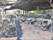  ??  ?? Un oficial de Policía verifica el lote de vehículos que fue incendiado por los sicarios en la huida hacia el Brasil.