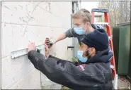  ?? PHOTO PROVIDED ?? Jayden Brown, front,, shows Ulster BOCES Career & Technical Center student Eric Oakley of the Rondout
Valley Central School District how to hang a bracket on the outside wall to hold the heating system’s condenser.