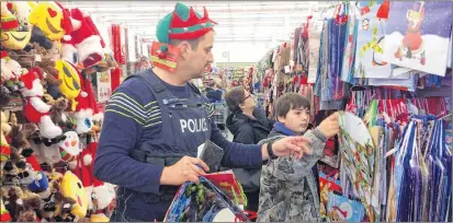  ?? ERIC BOURQUE ?? Const. Laurent Boucher of the Yarmouth town detachment of the RCMP helps Central School student Cameron Rhyno do some shopping at Dollarama on Dec. 11 as part of this year’s Cop Shop initiative.