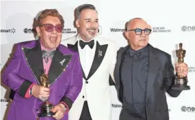  ?? MICHAEL TRAN/AFP VIA GETTY IMAGES ?? John, left, his husband David Furnish and Taupin celebrate after the Oscars this year. John and Taupin took home best original song for “(I’m Gonna) Love Me Again” from John’s biopic “Rocketman.”