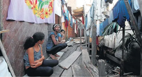  ?? JF DIORIO / ESTADÃO ?? Abandono. Em março, Carla Renata (c) escapou de uma enchente no Rio Pequeno, em São Paulo, fugindo pelo buraco aberto na parede de um vizinho