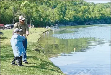  ?? (NWA Democrat-Gazette/Sally Carroll) ?? Cade Winkelmann and dad Kyle land a fish at Lake Ann on May 2 as Grandpa Alan Terrell looks on in Bella Vista.