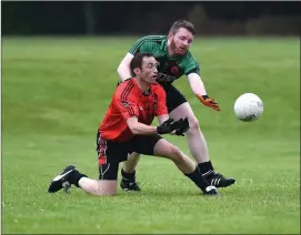  ??  ?? Domhaill O’Sullivan Fossa hand passes the ball challenged by Shane Kenny Churchill in the Kerry County Credit Union league at Fossa on Saturday